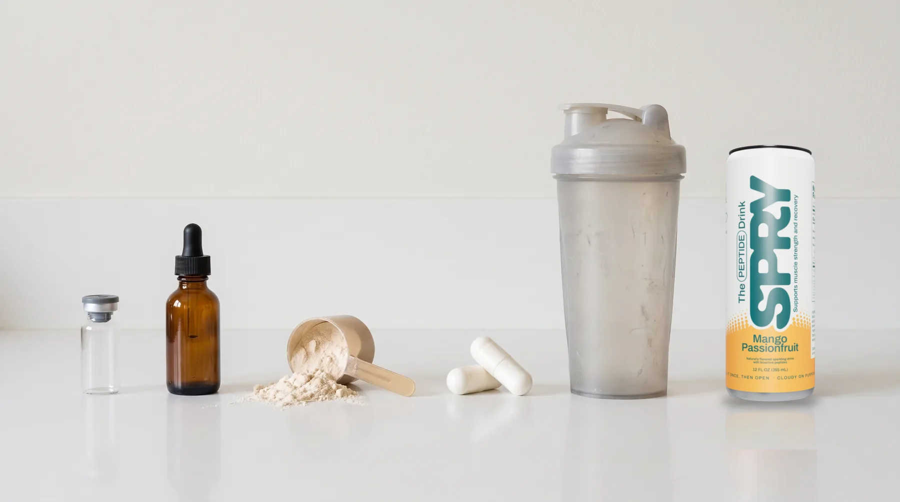 A counter lined with a vial, a dropper bottle, a scoop of powder, two large capsules and a shaker bottle, and at the end a cold can of Spry